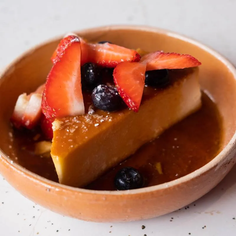 Panfila flan with caramel and fresh strawberries in a terracotta dish