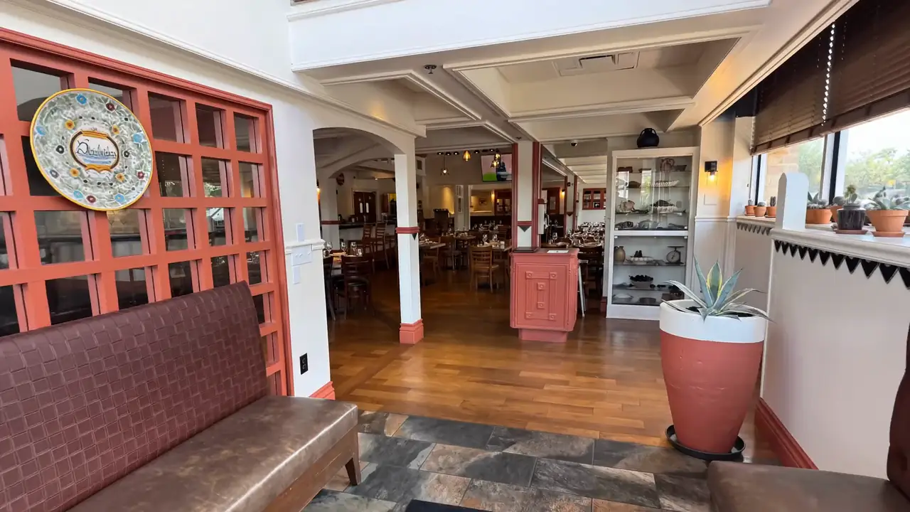The dining room at Panfila Cocina Mexicana, looking through terracotta French doors past a talavera plate to farm tables and burgundy booths